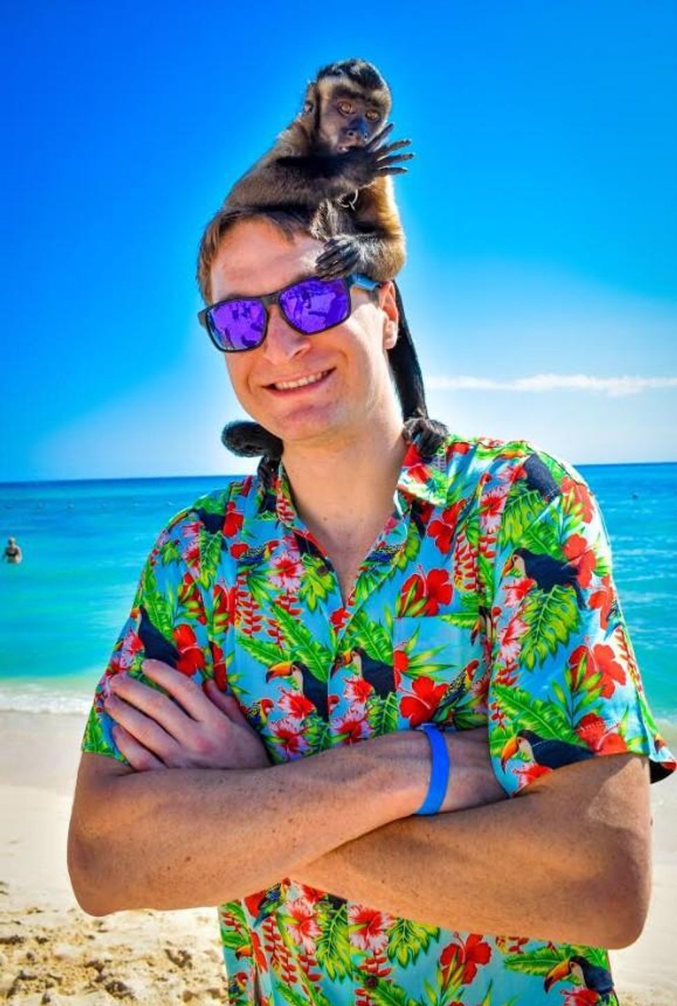 Person standing with the Hawaiian shirt with a monkey on their head