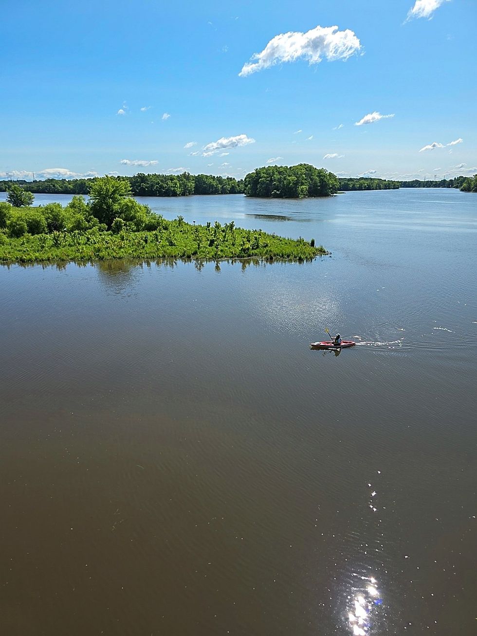 Personne en kayak sur rivi\u00e8re calme et verdoyante.