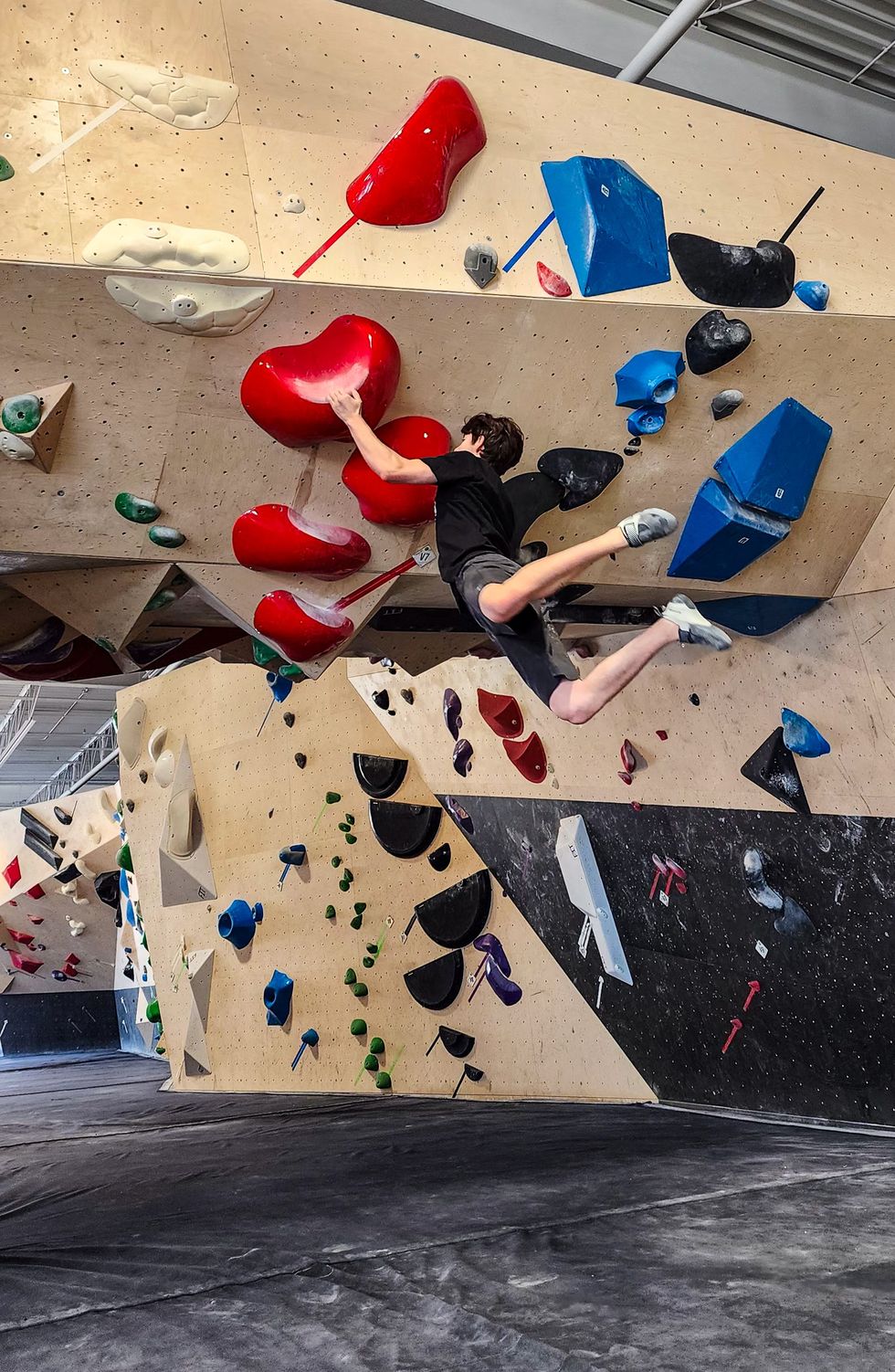 Personne en plein mouvement sur un mur d'escalade int\u00e9rieur \u00e0 Bloc Action, Terrebonne