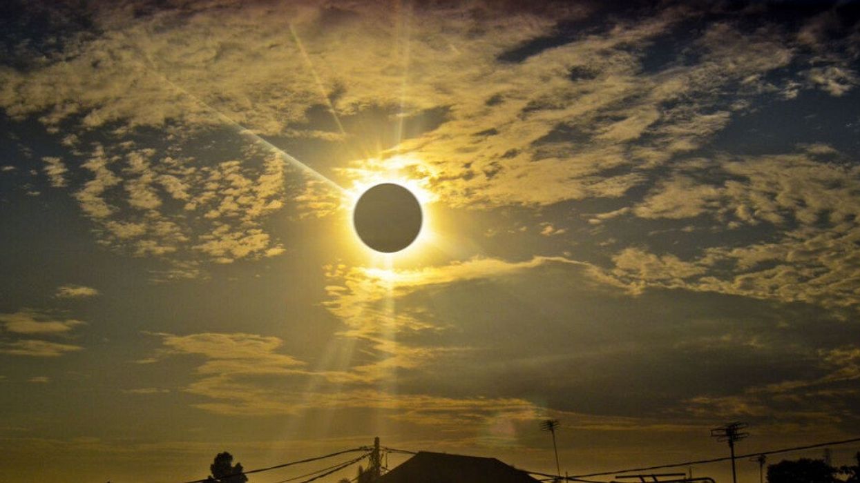 Photo d'une éclipse solaire, prise de loin dans un quartier résidentiel.