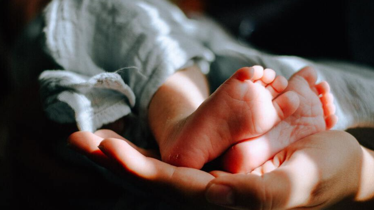 Pieds de bébé tenus par une main adulte.