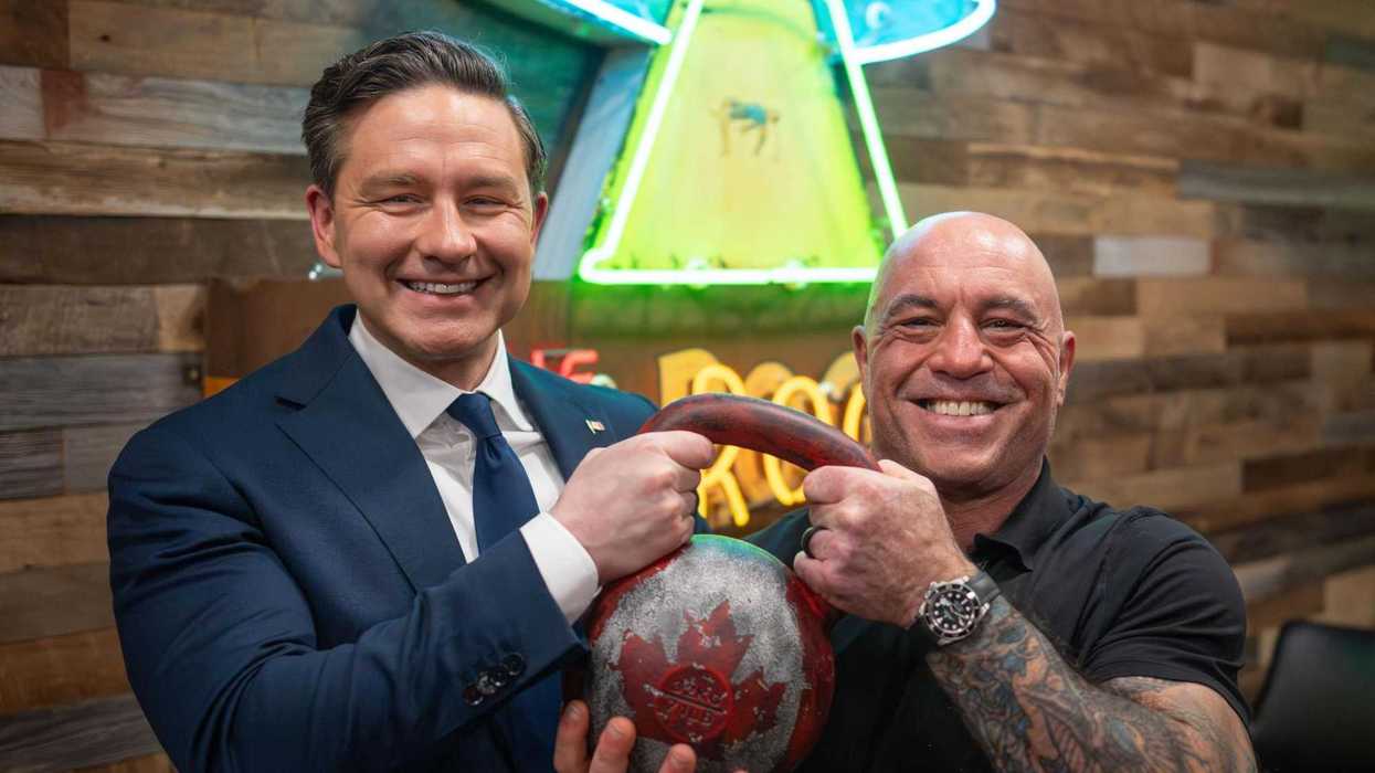 Pierre Poilievre and Joe Rogan pose for a photo holding a kettlebell with the Canadian flag on it.