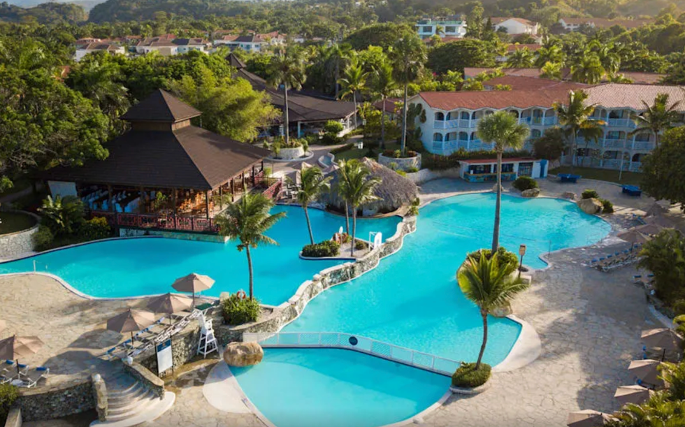 Piscine avec palmiers, bar et h\u00f4tel autour.