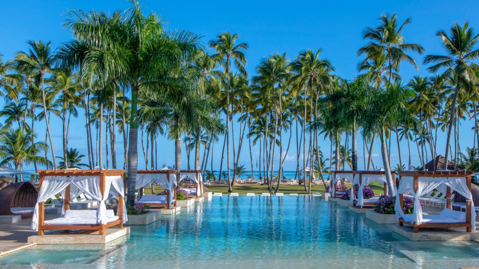 Piscine avec palmiers et chaises longues avec voiles de l\u2019h\u00f4tel Viva V Samana by Wyndham \u00e0 Samana en R\u00e9publique dominicaine.