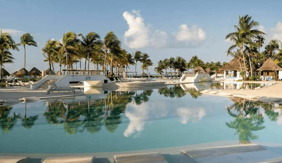 Piscine bord\u00e9e de palmiers au Bluebay Grand Esmeralda dans la Riviera Maya au Mexique.
