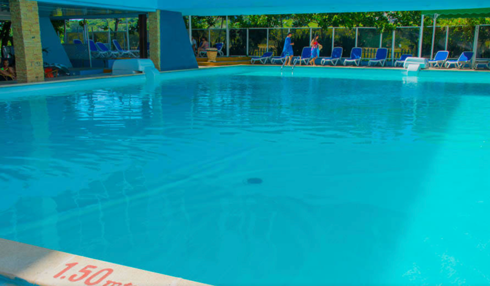 Piscine d'un h\u00f4tel entour\u00e9e de chaises longues.