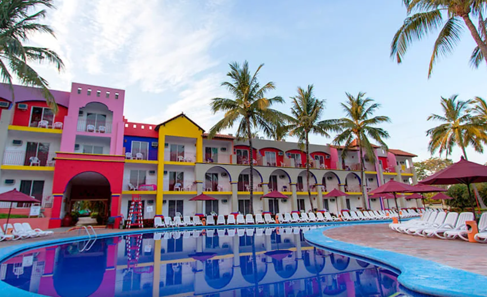 Piscine entour\u00e9e de b\u00e2timents color\u00e9s au Grand Decameron Complex \u00e0 Riviera Nayarit.