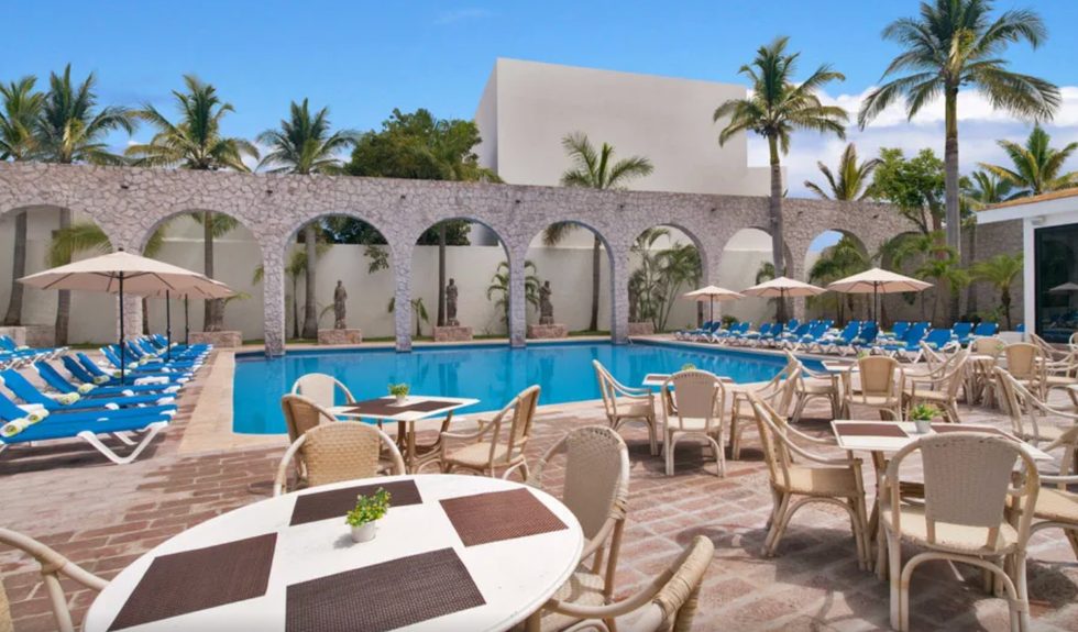 Piscine entour\u00e9e de chaises longues, de tables et de chaises.