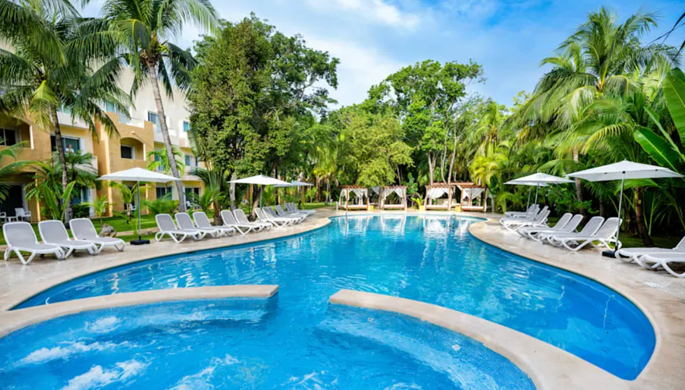 Piscine ext\u00e9rieure entour\u00e9e de palmiers dans un resort tout inclus pr\u00e8s de Santo Domingo en R\u00e9publique dominicaine.