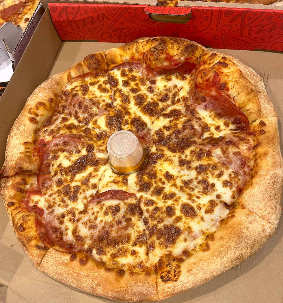 Pizza au pepperoni et fromage dans sa bo\u00eete : elle semble app\u00e9tissante et bien huileuse.