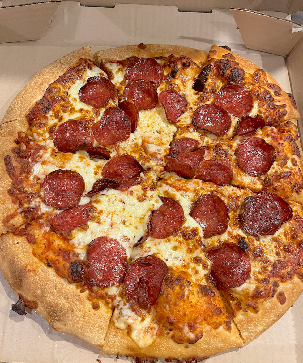 Pizza au pepperoni et fromage dans sa bo\u00eete : elle semble bien huileuse et grill\u00e9e.