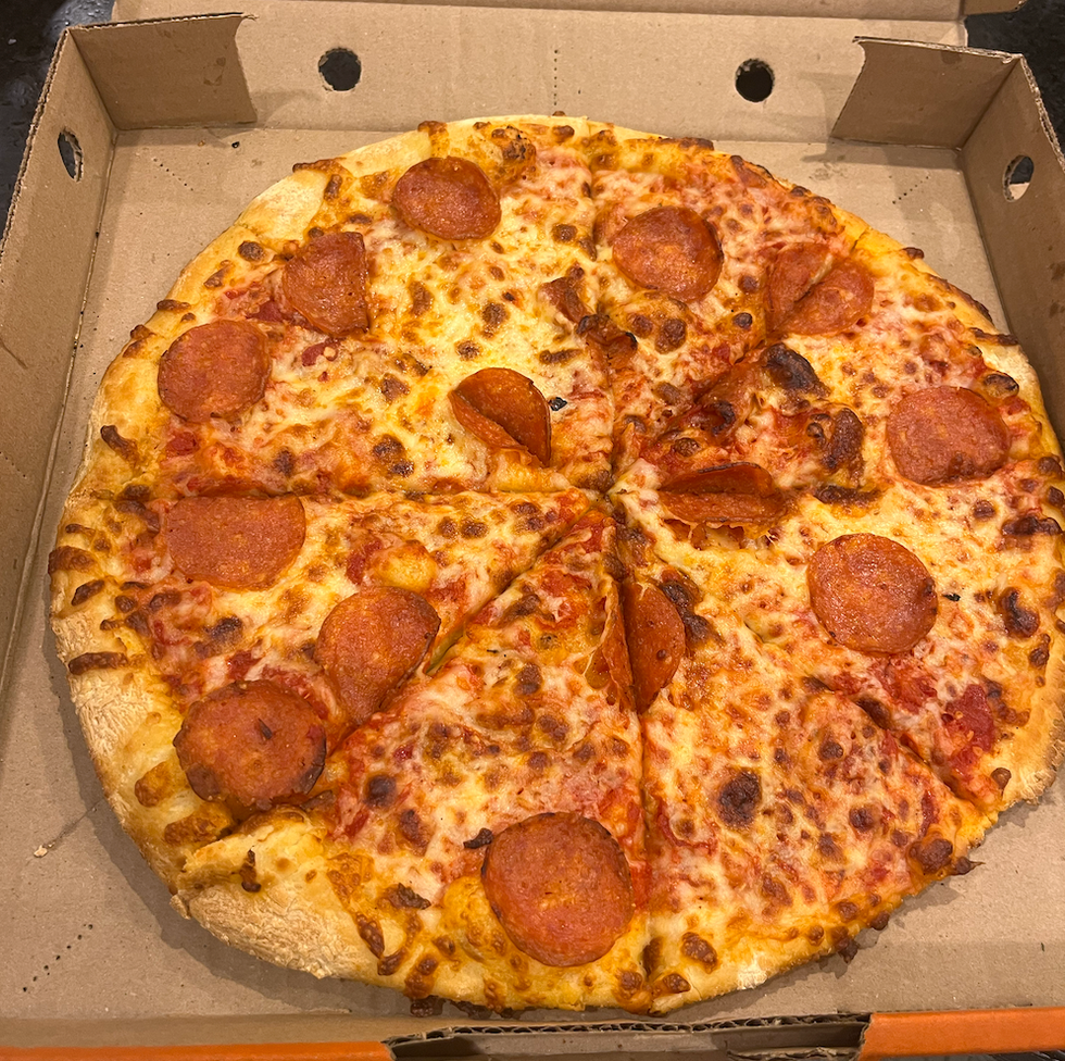 Pizza au pepperoni et fromage dans sa bo\u00eete : elle semble manquer d'ingr\u00e9dients et de cuisson.