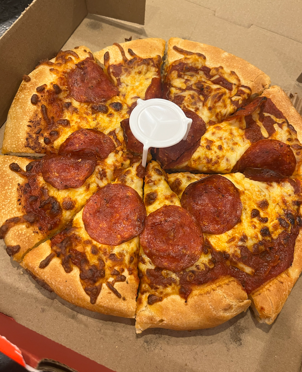 Pizza au pepperoni et fromage dans sa bo\u00eete : elle semble manquer de fromage, mais elle est bien cuite.