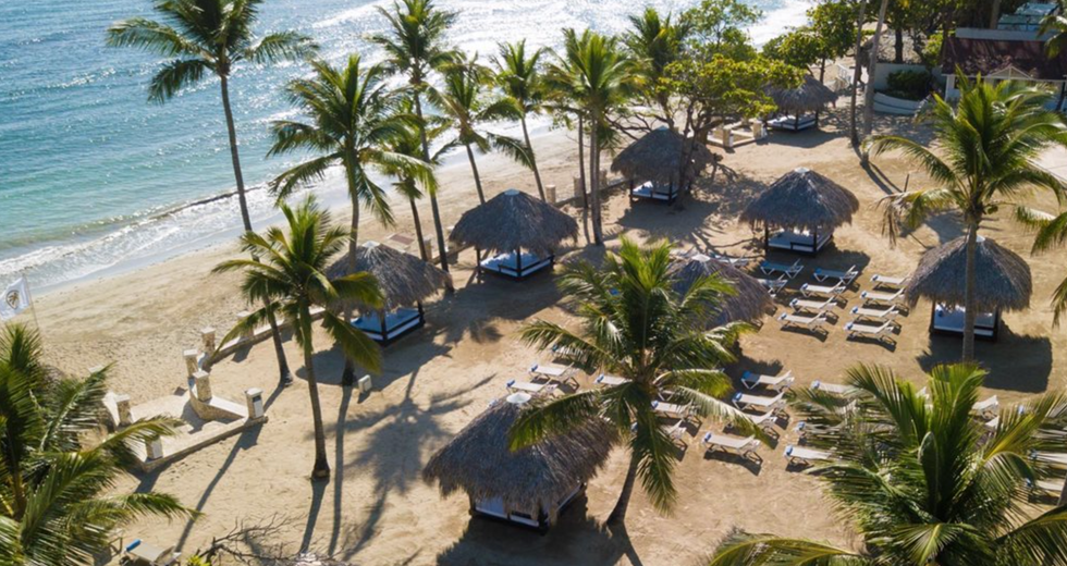 Plage priv\u00e9e avec lits, palmiers et chaises longues au Cofresi Palm Beach and Spa Resort en R\u00e9publique dominicaine