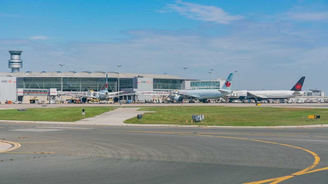 planes and terminal at toronto pearson airport with air traffic control tower in background