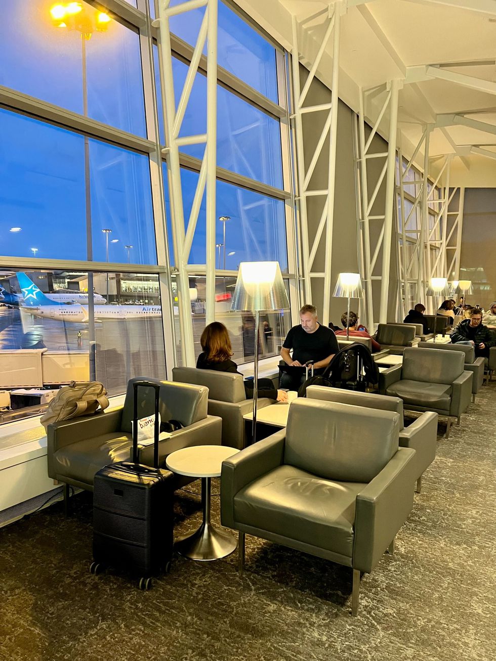 Plusieurs fauteuils sont install\u00e9s \u00e0 l'int\u00e9rieur du salon VIP d'Air Canada, donnant une vue sur les avions \u00e0 l'a\u00e9roport de Montr\u00e9al.