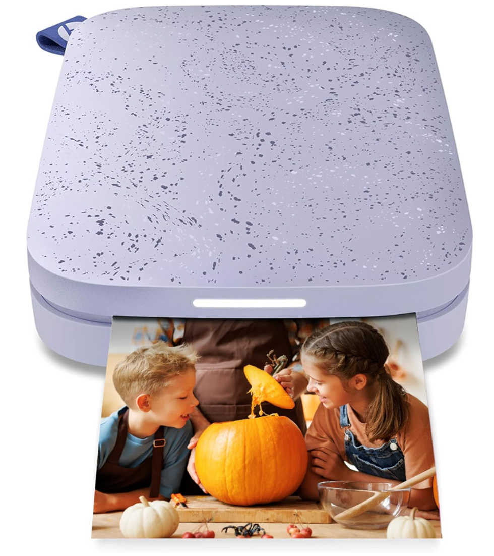 Portable instant photo printer printing a photo of two kids carving a pumpkin.