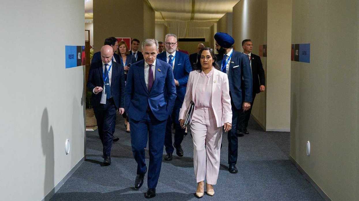 Prime Minister Mark Carney and Foreign Affairs Minister Anita Anand walk down a hallway.