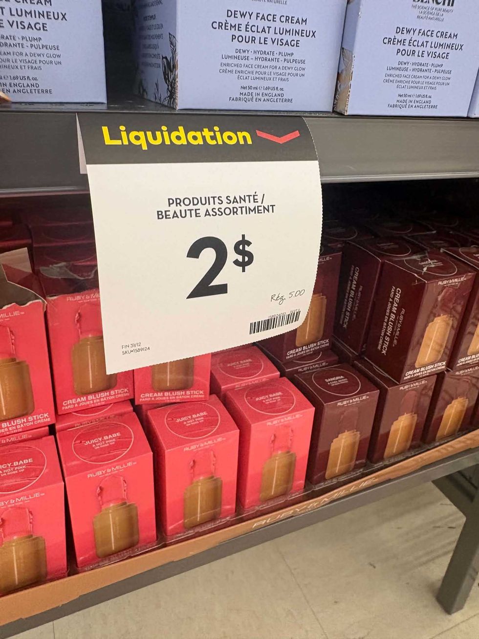 Produits de maquillage Ruby & Millie, dont des b\u00e2tons de fard \u00e0 joues, sous une affiche de liquidation \u00e0 2 $.