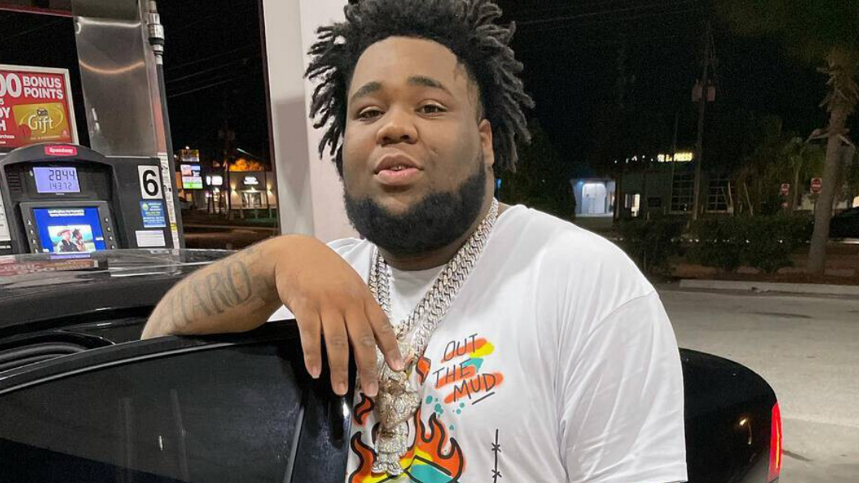 Rapper Rod Wave leaning on a car at the gas station.
