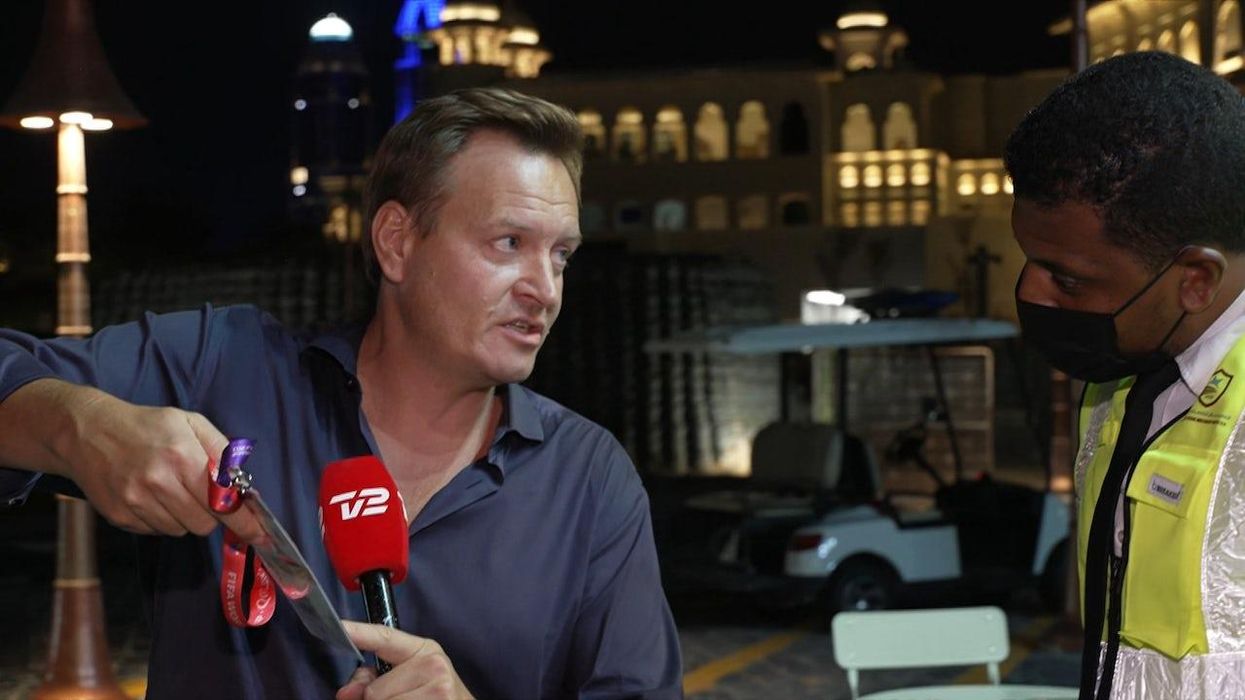 Rasmus Tantholdt showing the security guard proof of accreditation while being interrupted on air.