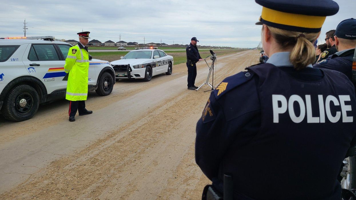 RCMP officers in Manitoba by cars on the road.