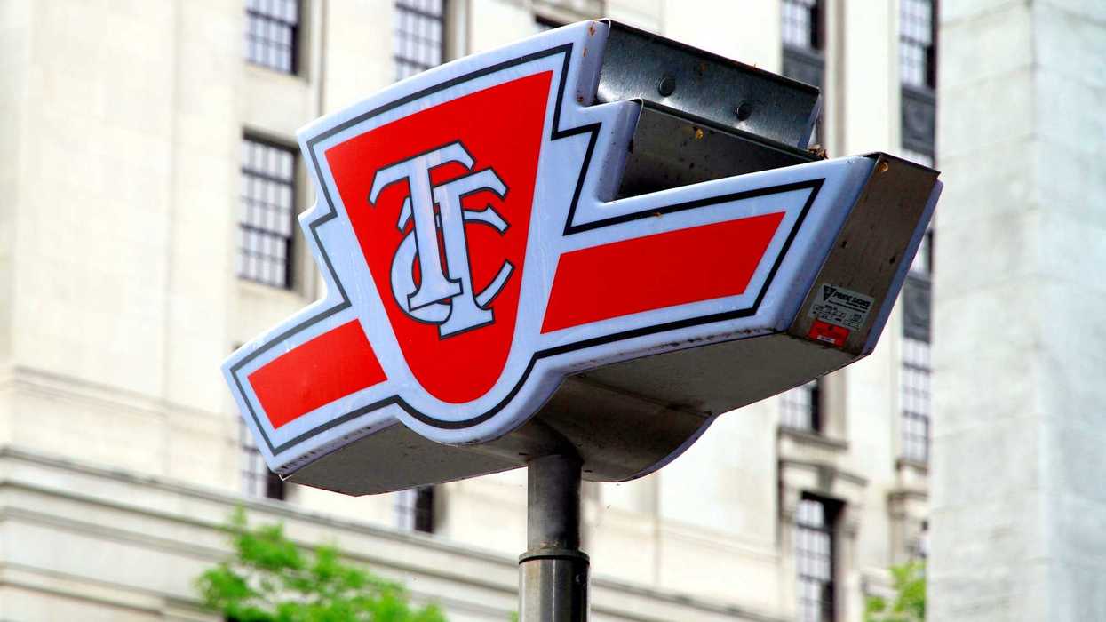 red and white ttc sign in front of building and trees in toronto