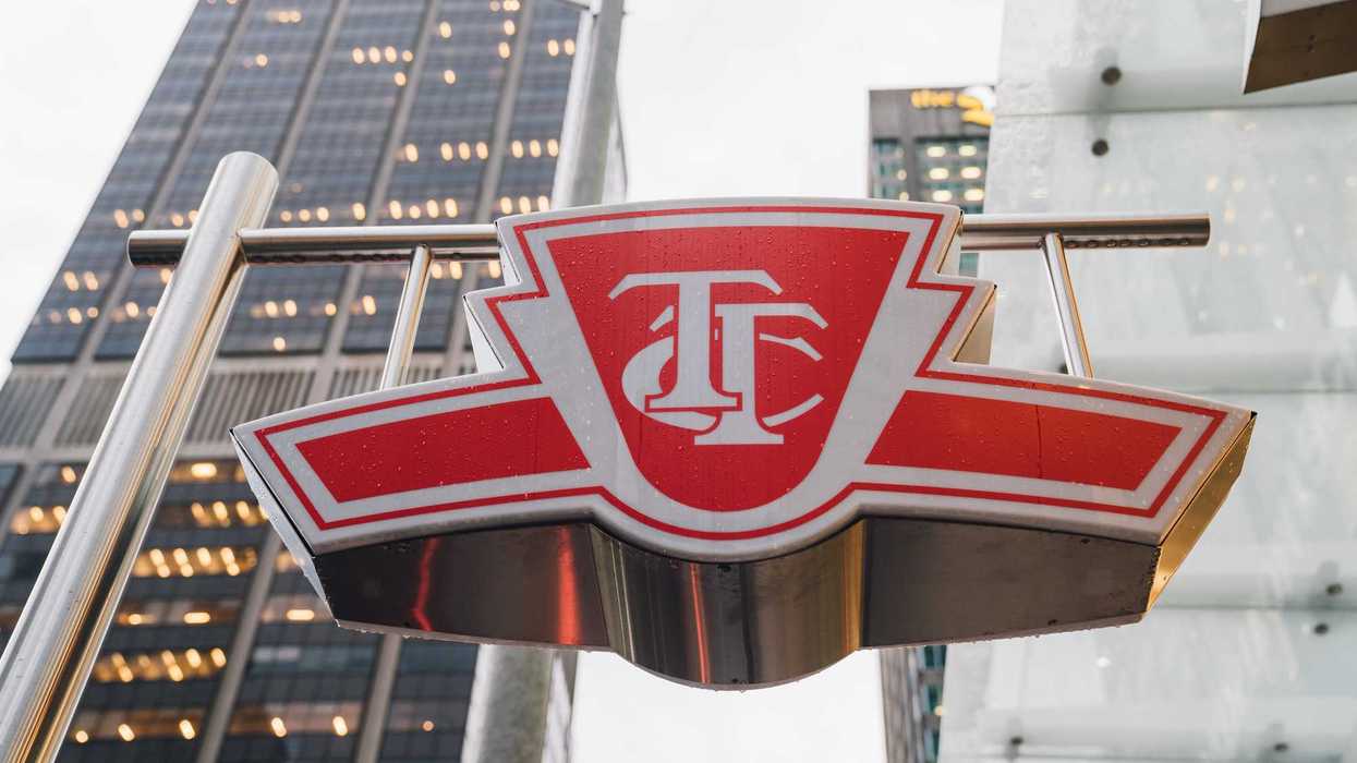 red and white ttc sign with buildings in background