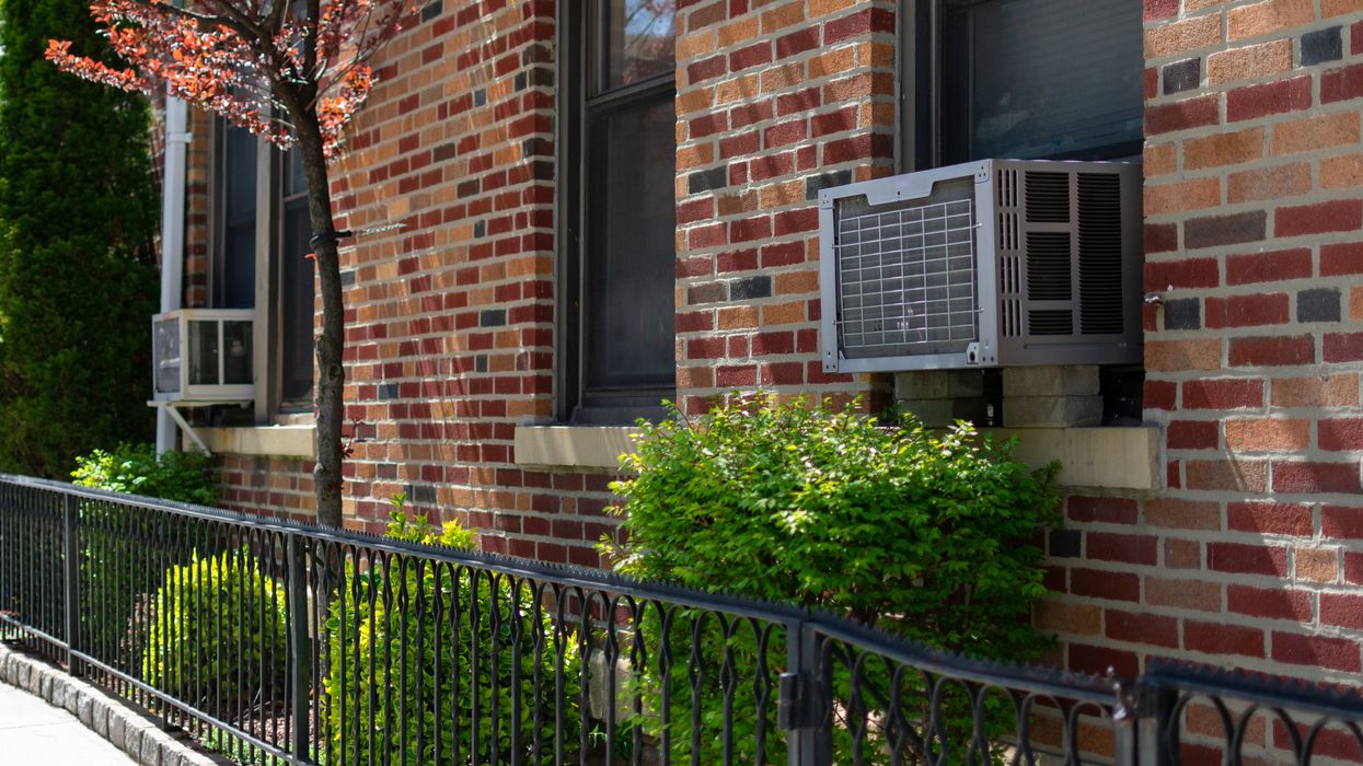 Red brick building with air conditioning units in windows (illustrative).