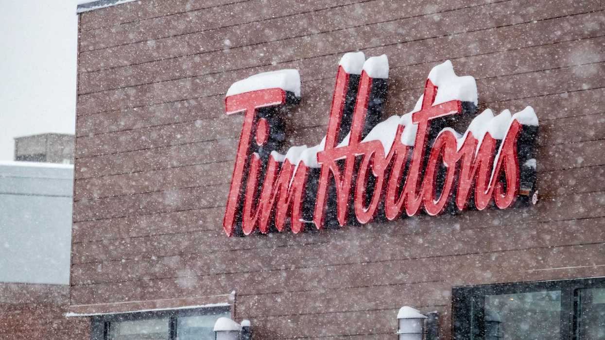 red tim hortons sign covered in snow on exterior of restaurant