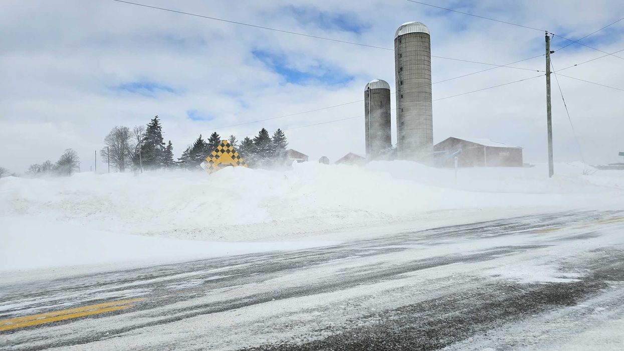 road in ontario with snow banks and blowing snow
