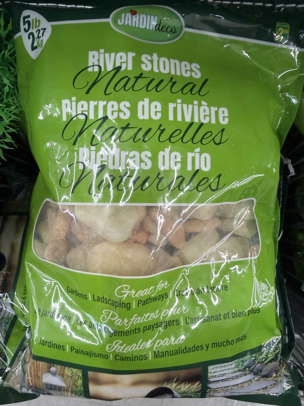 Rocks in a clear and green bag on a store shelf.