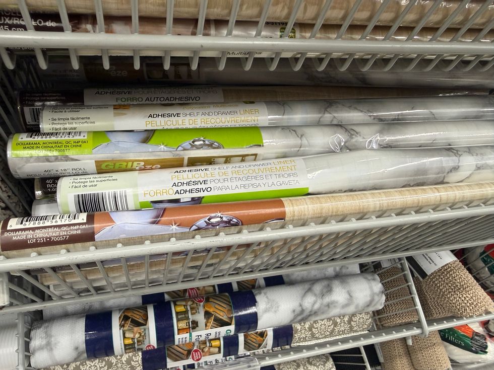 Rolls of material in various shades and designs that says adhesive shelf and drawer liner on them.