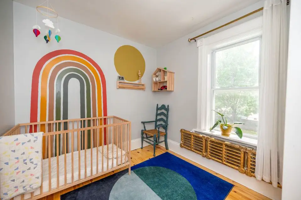 Room with a crib and rainbow on the wall.