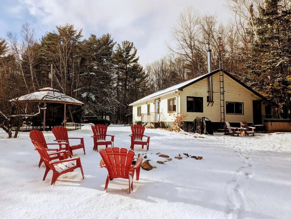 Rustic cottage in the winter with a fire pit and an outdoor hot tub.