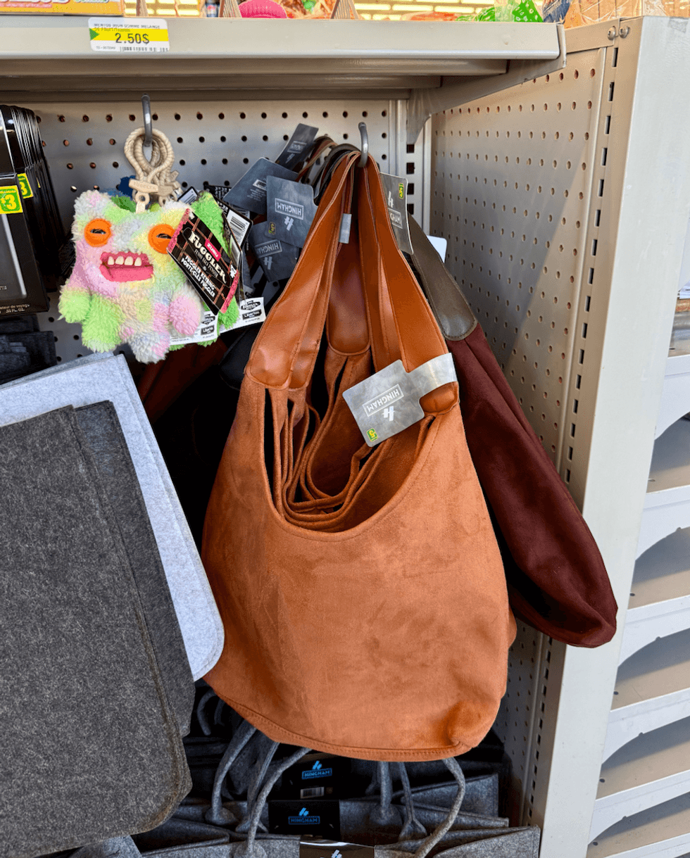 Sacs \u00e0 main souples \u00e0 effet su\u00e8de de couleur cognac et bourgogne, suspendus dans une all\u00e9e du Dollarama.