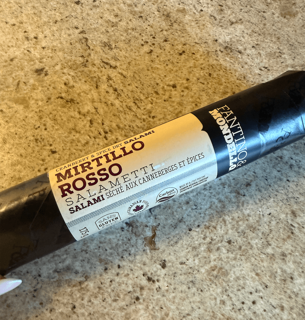 Salami s\u00e9ch\u00e9 Mirtillo Rosso aux canneberges et \u00e9pices achet\u00e9 au Liquidation Marie pos\u00e9 sur un comptoir.