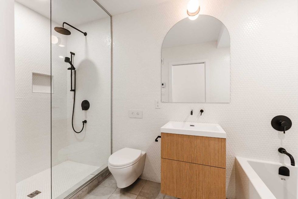 Salle de bain contemporaine avec douche vitr\u00e9e et accents noirs mats.
