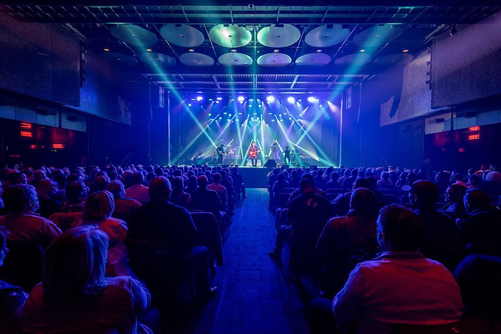 Salle de spectacle bond\u00e9e avec un groupe de musique sur sc\u00e8ne.