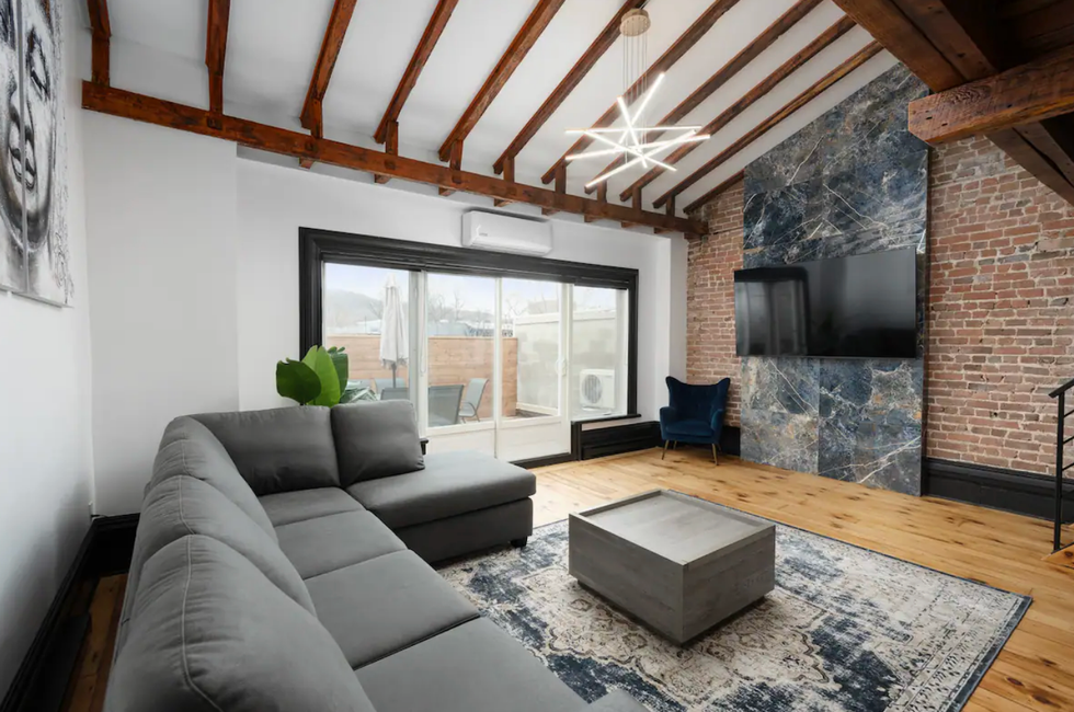 Salon d'un loft avec un canap\u00e9 gris et une porte-patio.