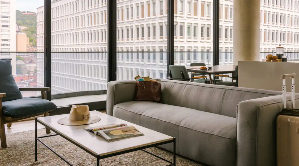 Salon d'un logement avec baie vitr\u00e9e, canap\u00e9, chaises et une table.