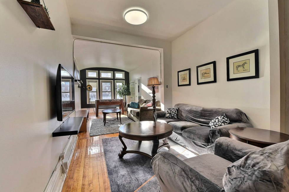 Salon d'un logement avec deux canap\u00e9s gris et une grande fen\u00eatre.