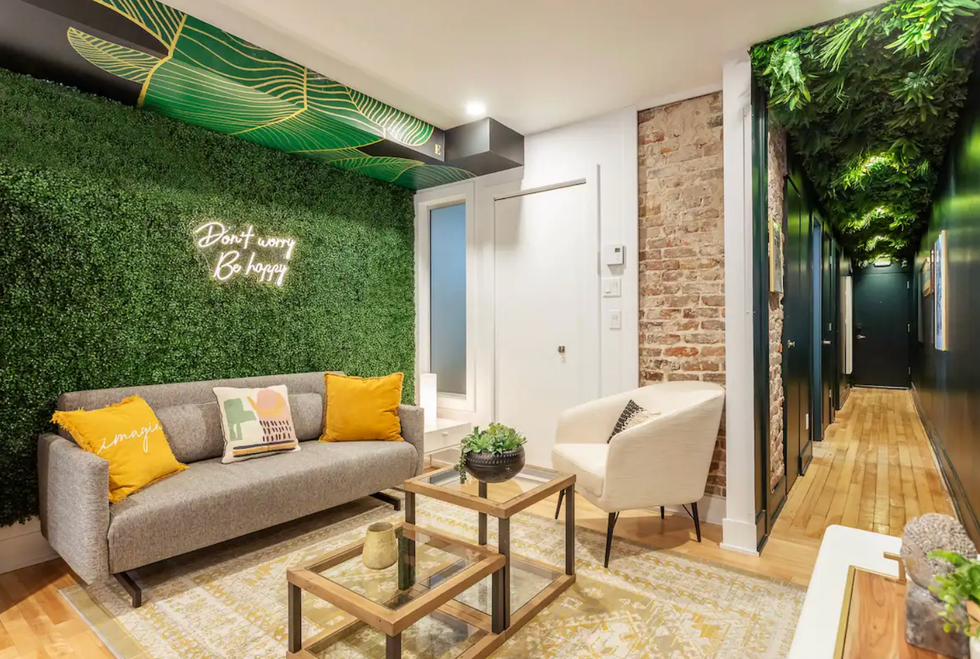 Salon d'un logement avec du faux gazon au mur et des feuilles au plafond.