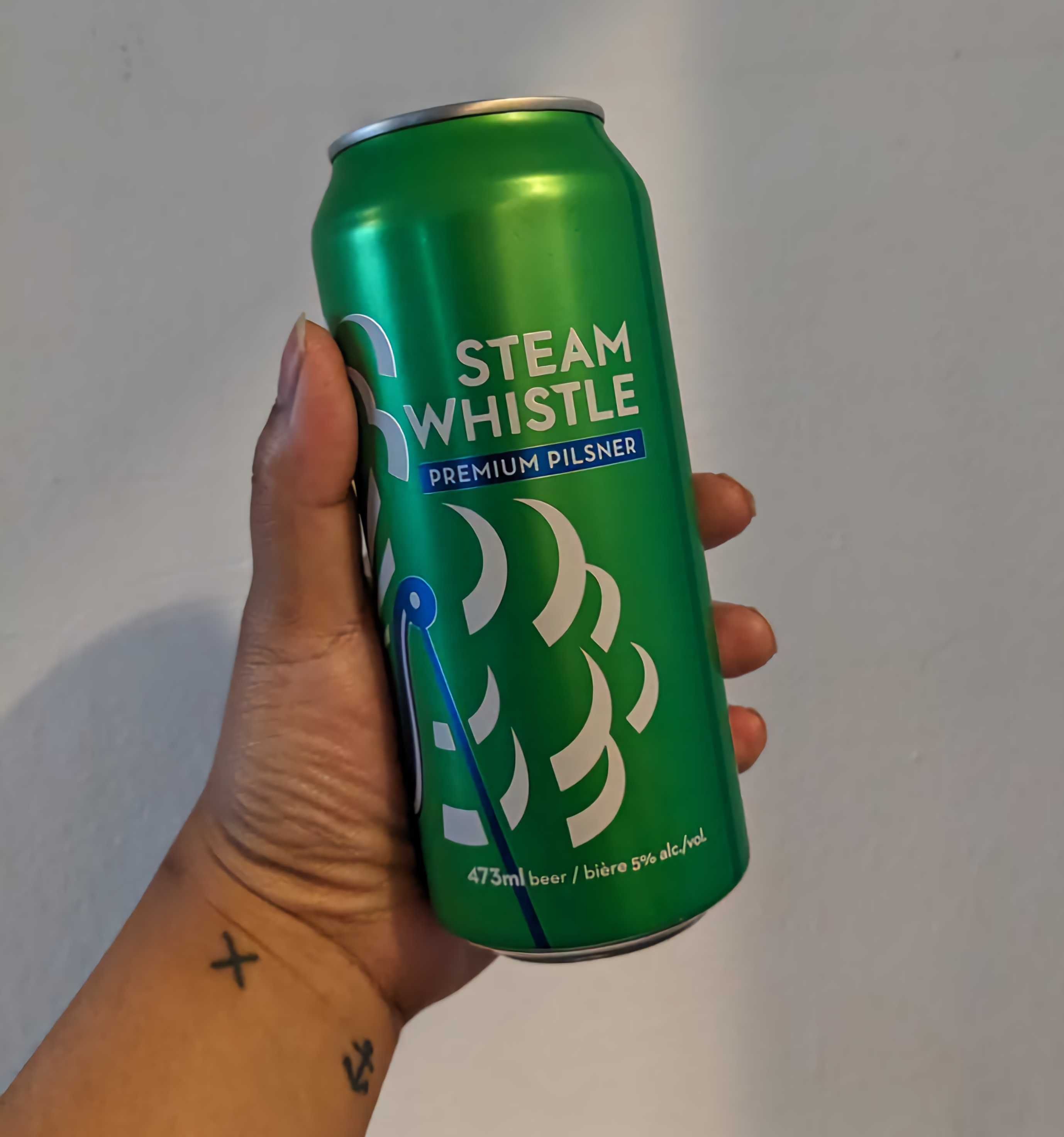 Sarah holding a can of Steam Whistle Premium Pilsner from the LCBO.