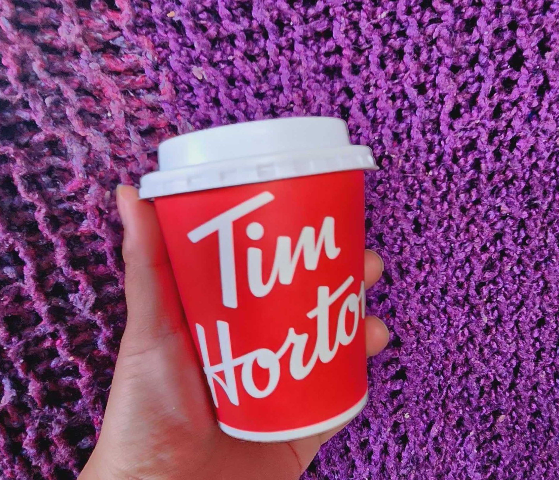 Sarah holding a coffee from Tim Hortons fro