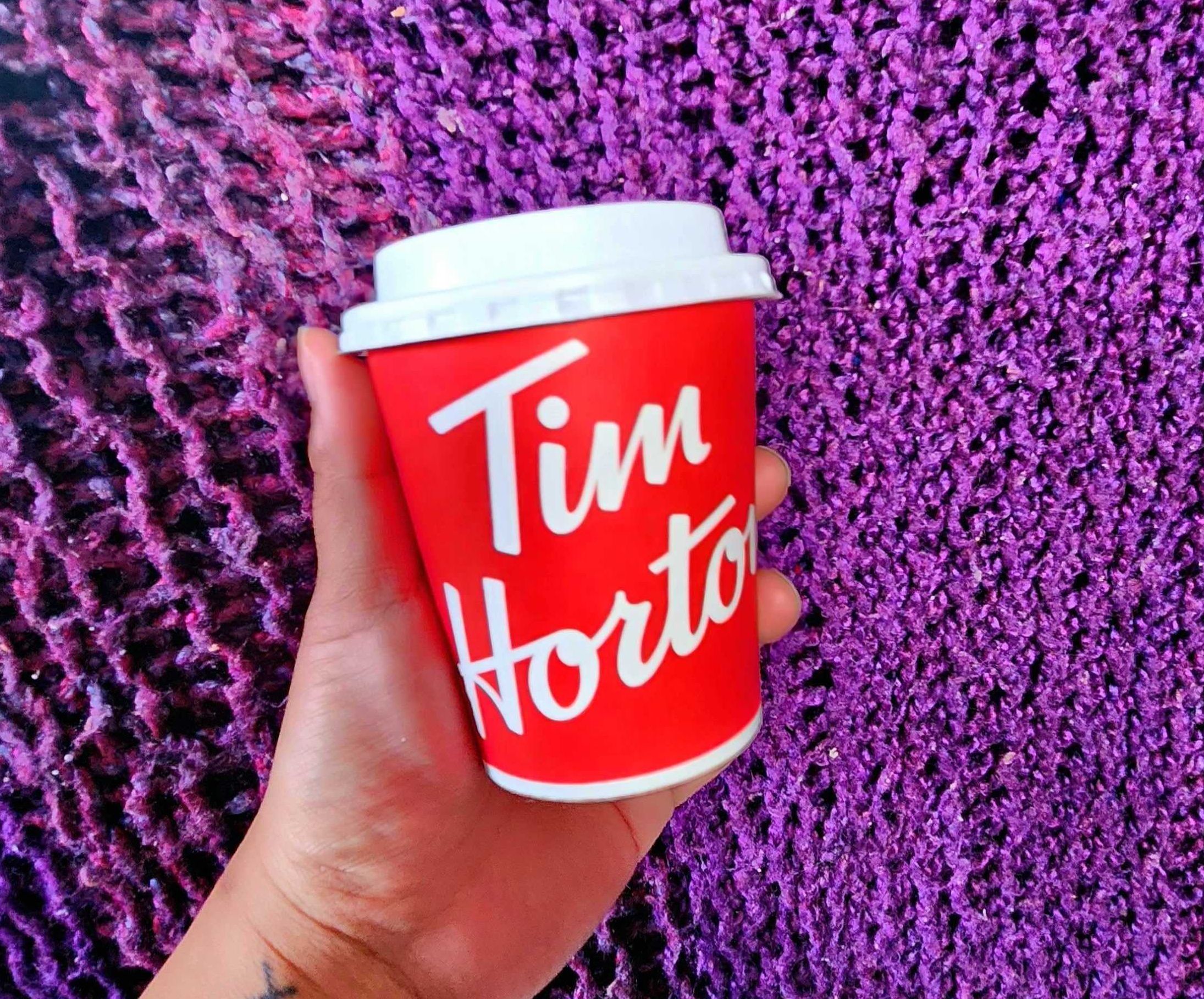 Sarah holding a small Tim Hortons coffee.