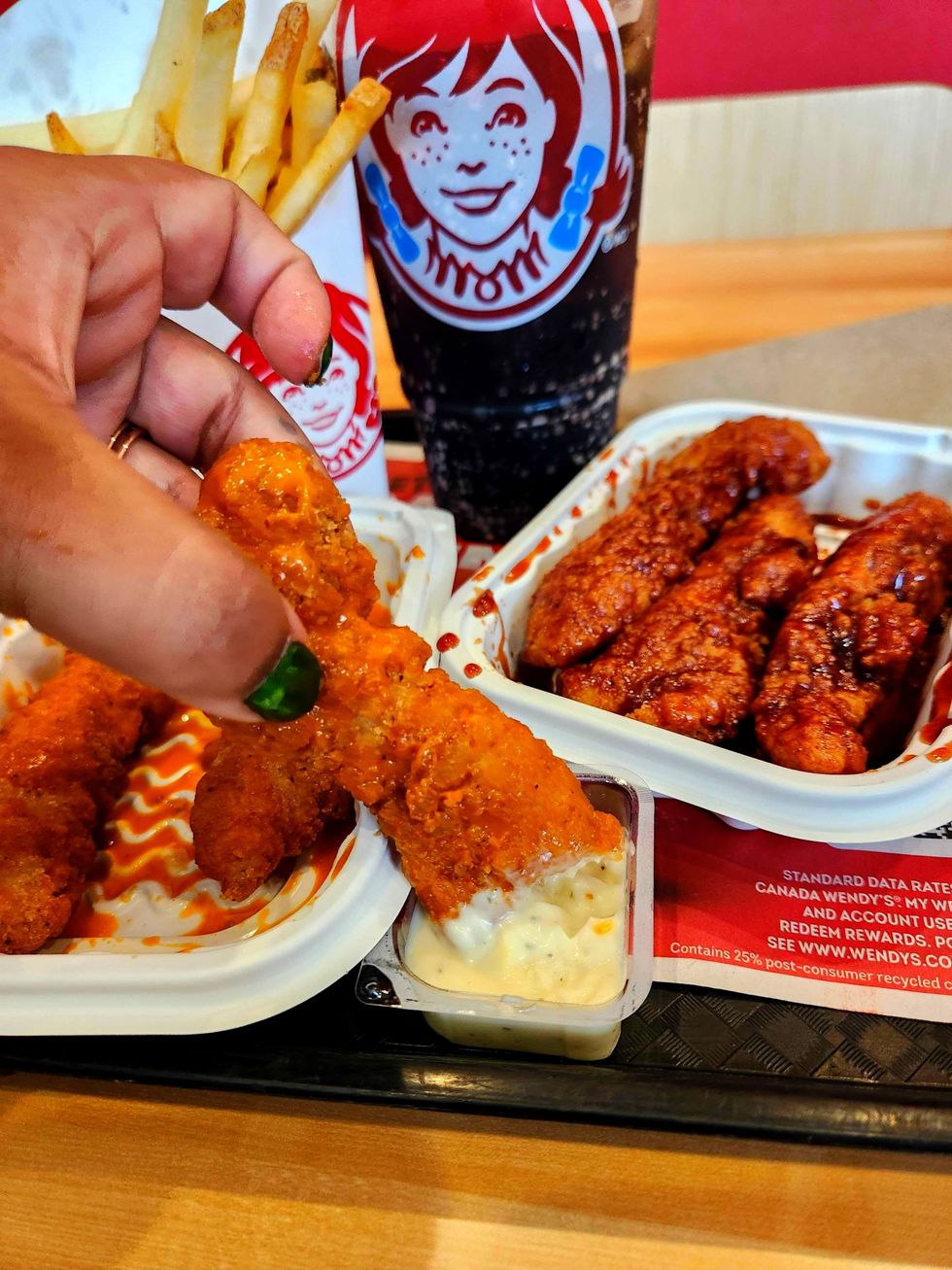Saucy Chicken Strips from Wendy's being dipped ranch sauce.