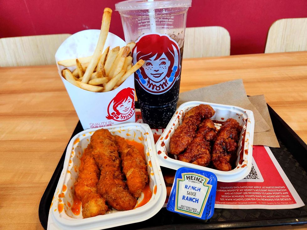 Saucy Chicken Strips from Wendy's on a tray with a drink, fries and ranch sauce.