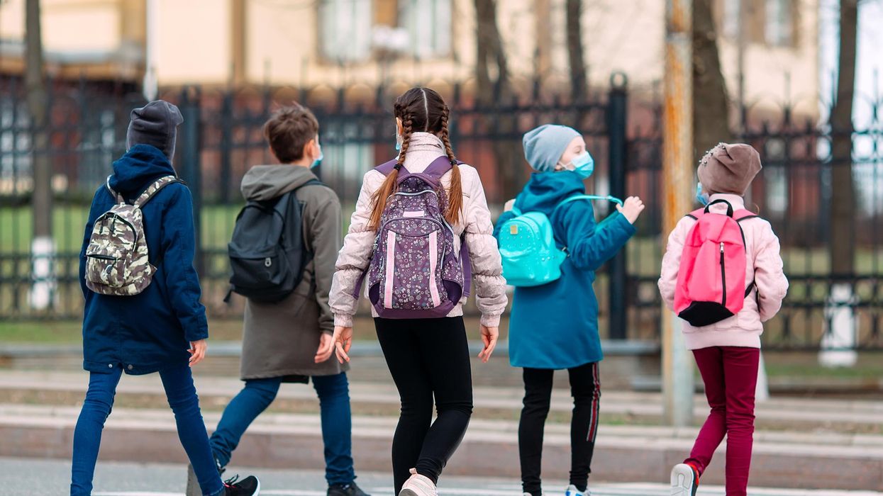 School children cross the road in medical masks.