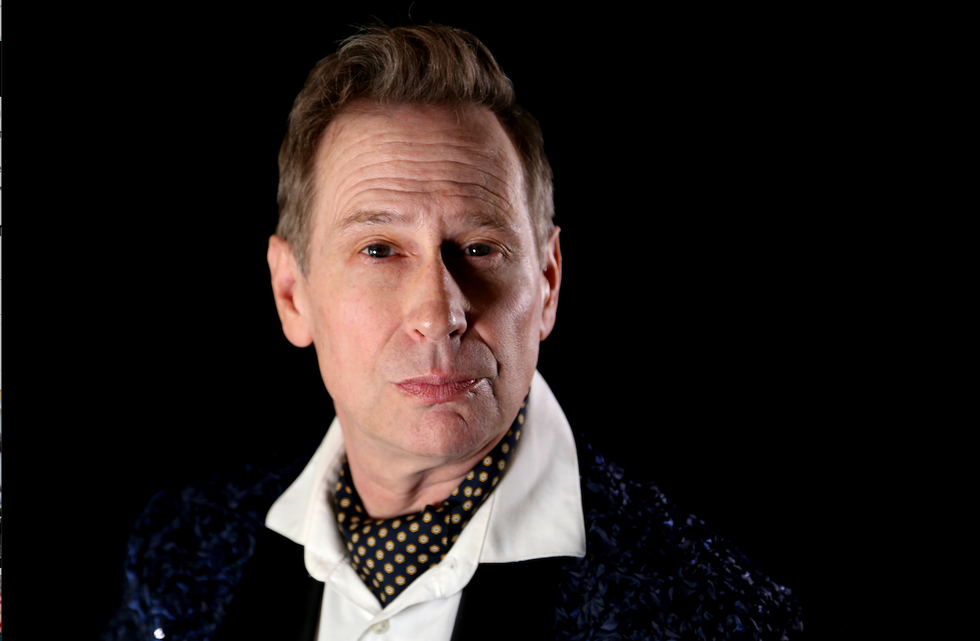 Scott Thompson in character as Buddy Cole with polka dot cravat, white dress shirt and textured dinner jacket. 